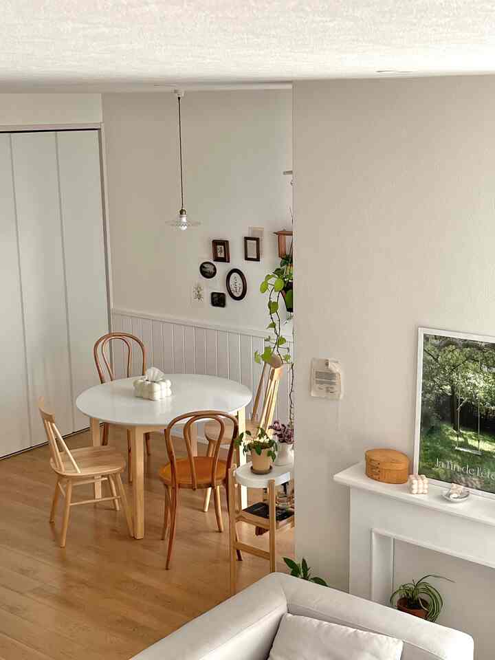 White and wood tone dining room featuring a round dining table and plants, creating a cozy and natural atmosphere