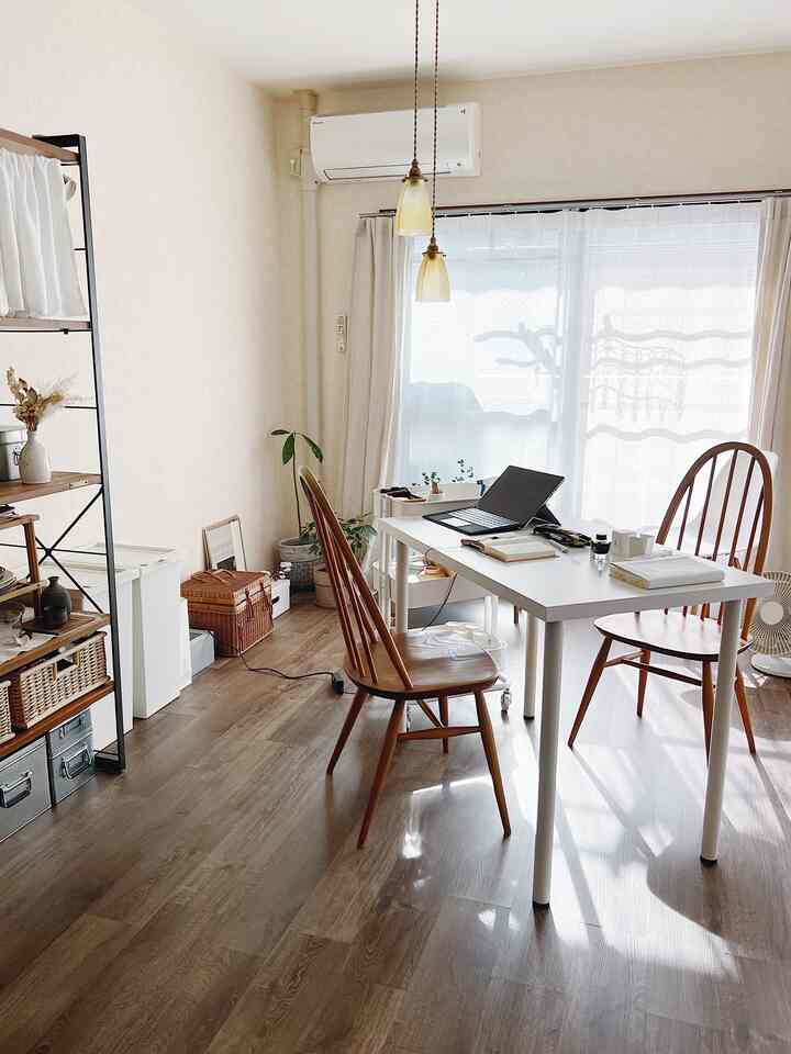 Bright beige and brown toned dining room featuring white table and wooden chairs, creating a cozy and natural home office atmosphere