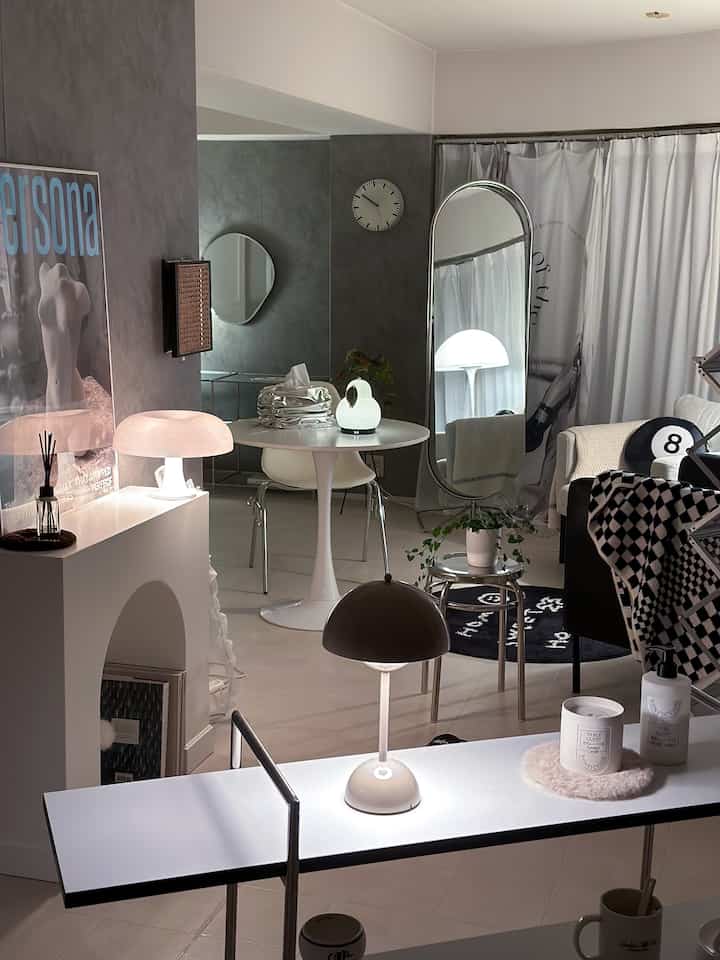 白とグレーの色調の2LDKリビングとダイニング、モダンなソファとテーブルランプ、大きな全身鏡が配置されたミニマルな空間