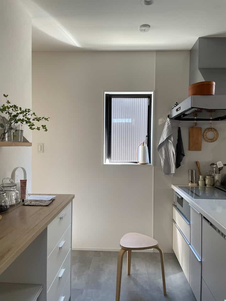 White and wood tone kitchen featuring a stool in the center, a modern and clean compact kitchen space