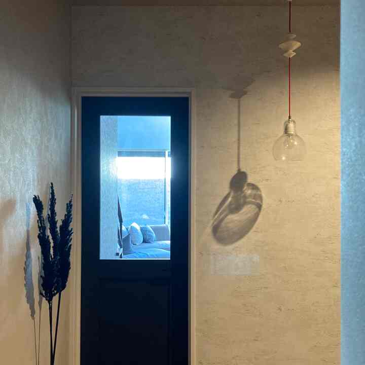 Natural-toned walls and transparent glass door with pendant light in a clean entrance space