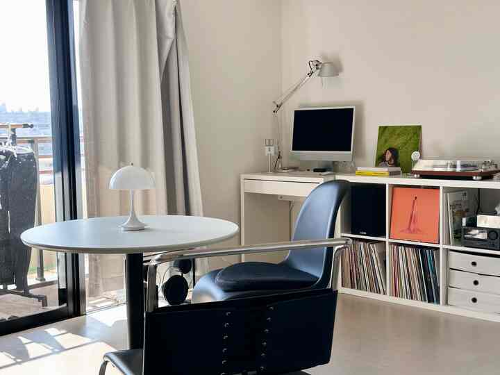 白とネイビーのトーンでまとめられた、ミニマルで清潔感のあるホームオフィスが配置されたリビングルーム