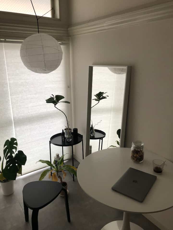White and black toned single household space featuring a round table, stool, plants, and a full-length mirror with a minimalist vibe