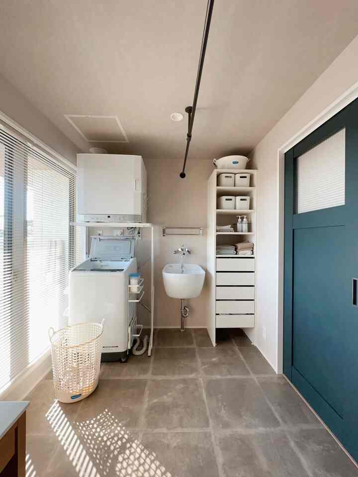 Beige-walled, white-furnished narrow small laundry room featuring a washer, storage shelves, and a ceiling-mounted hanger bar with clean atmosphere