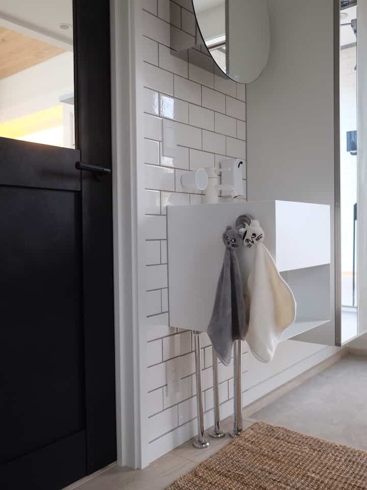 White and black toned entrance handwash area featuring cat face towels, creating a cozy and stylish atmosphere