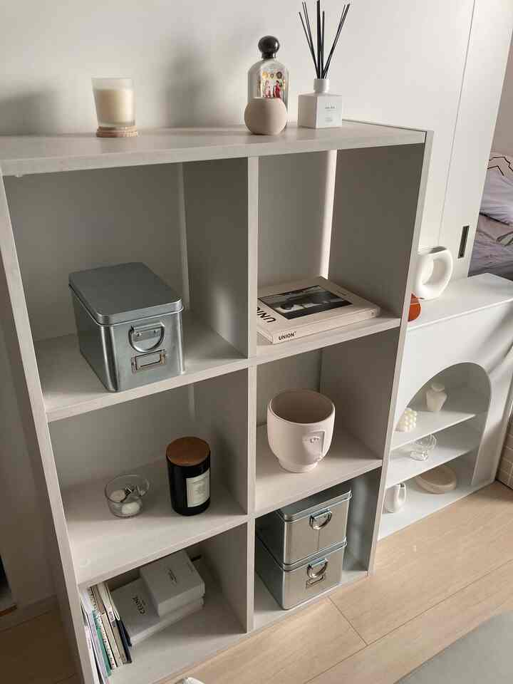 White and wood tone corner display storage unit featuring decorative objects, creating a modern and clean atmosphere