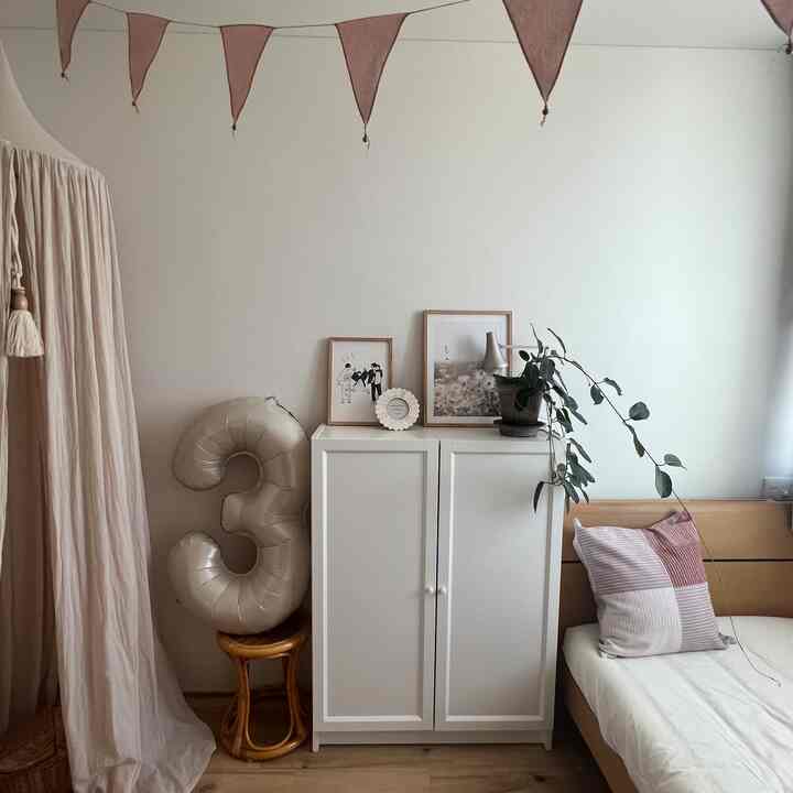 白とベージュの色調の子供部屋、大きな数字の風船と飾り付けがある雰囲気のある空間