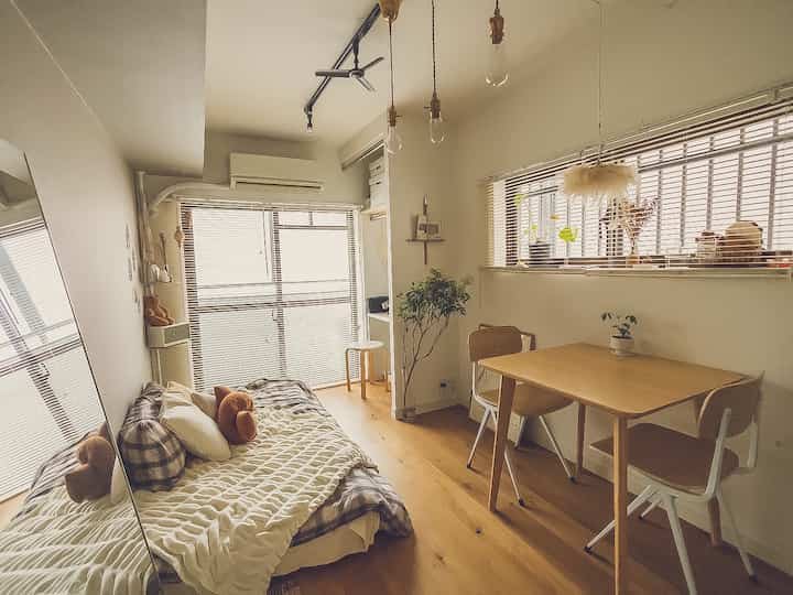 ナチュラルな木目調とシンプルなデザインの狭い一人暮らしダイニング、ソファベッドとブラインドが配置された空間