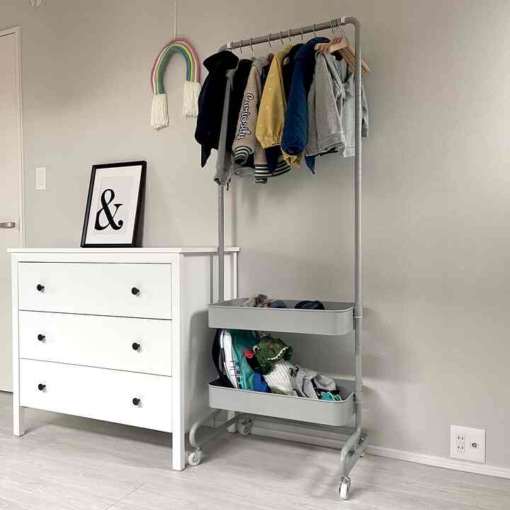 白とグレーのトーンの子供部屋、子供用の衣類ラックとチェストが整然と配置されたモダンな収納スペース