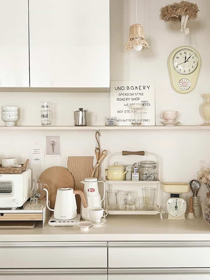Cozy kitchen in white and beige tones featuring an electric kettle and assorted kitchen accessories neatly arranged