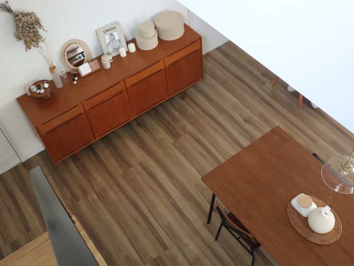 ウッドトーンのナチュラルなダイニングルーム、木製のダイニングテーブルとキャビネットが配置された清潔感のある居心地の良い空間