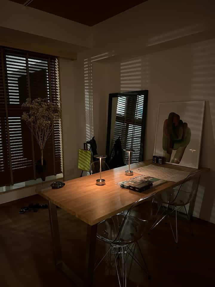 Dining room featuring wood tones and black accents with transparent chairs and table lamps creating a sleek atmosphere