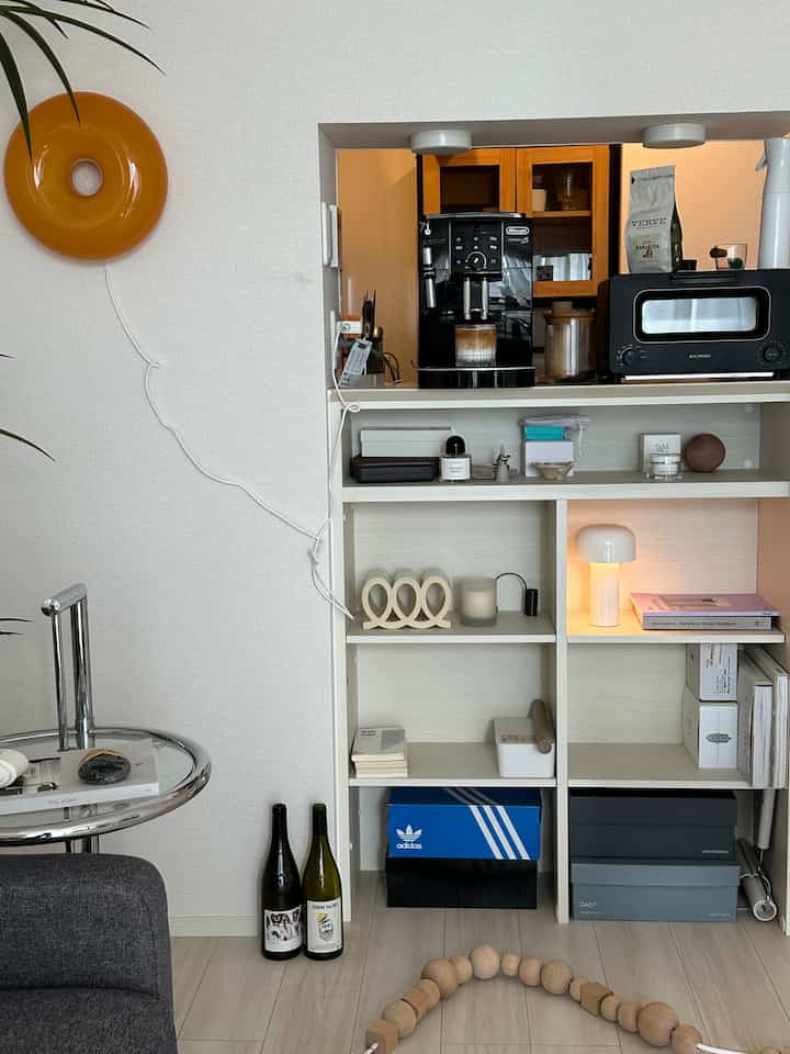 ホワイトとウッドトーンが調和したリビングの一角、整理された棚とホームカフェ用のコーヒー機器が配置された雰囲気のあるインテリア