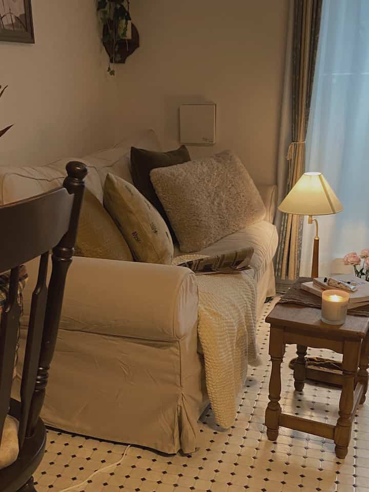 アイボリーとベージュの色調のリビング、快適なソファと木製のテーブル、温かみのある照明とキャンドルが配された雰囲気のあるインテリア