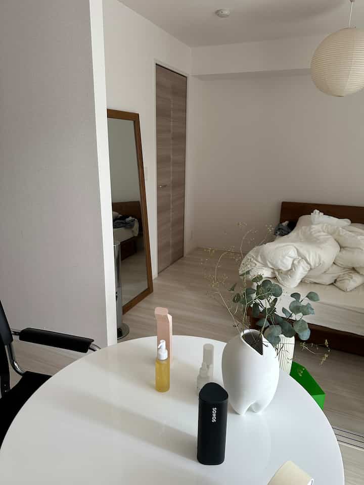 白と茶色のトーンの寝室、ミニマルな丸テーブルとベッドが配置された清潔感のあるインテリア