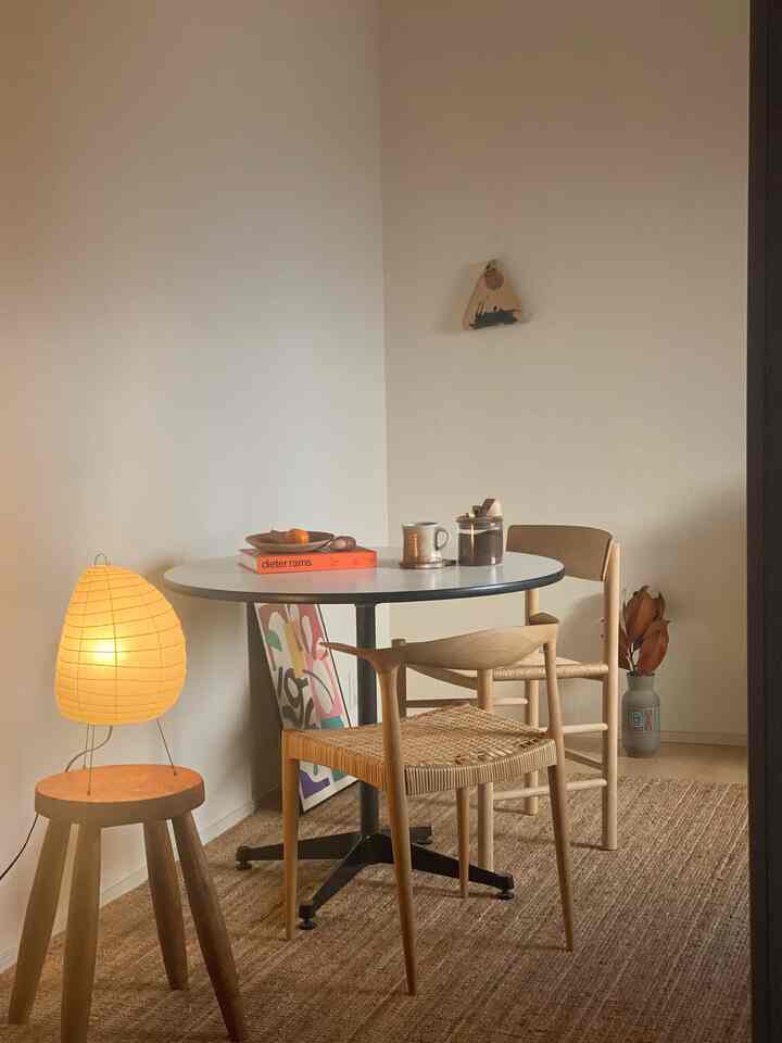 Light brown toned dining room featuring a round table, wooden chairs, and warm ambient lighting creating a cozy atmosphere