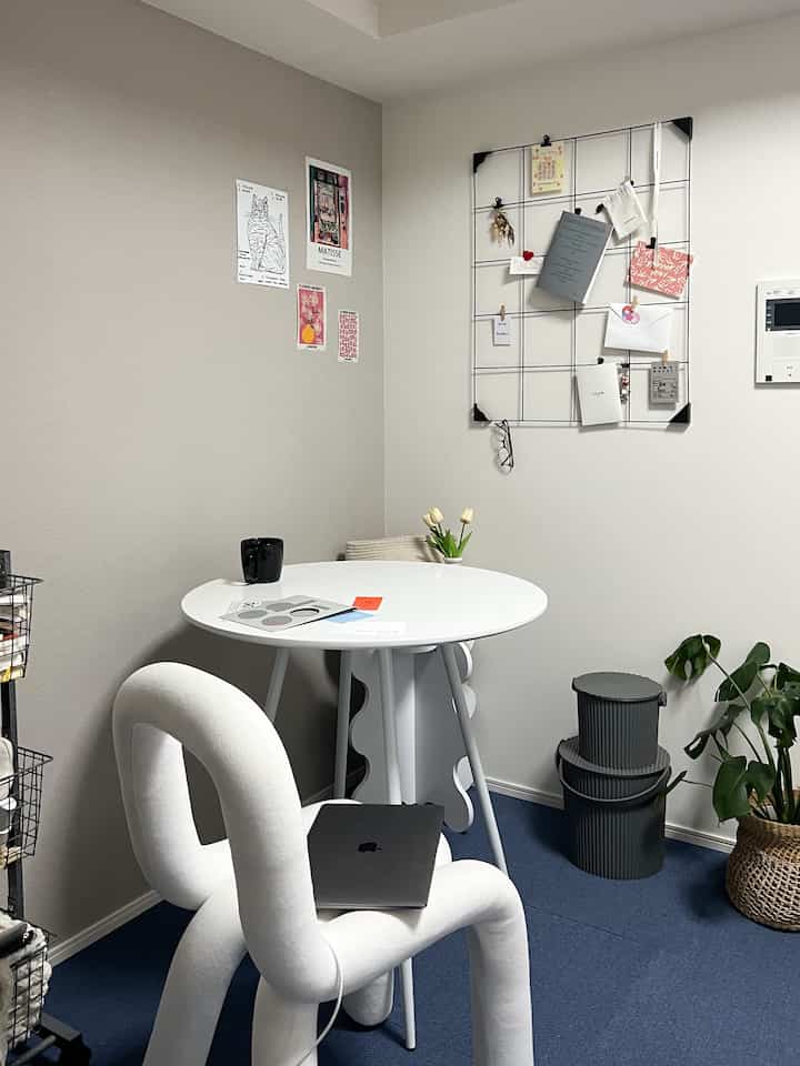 Small room in white and blue tones featuring a round dining table and a unique white chair with clean decor