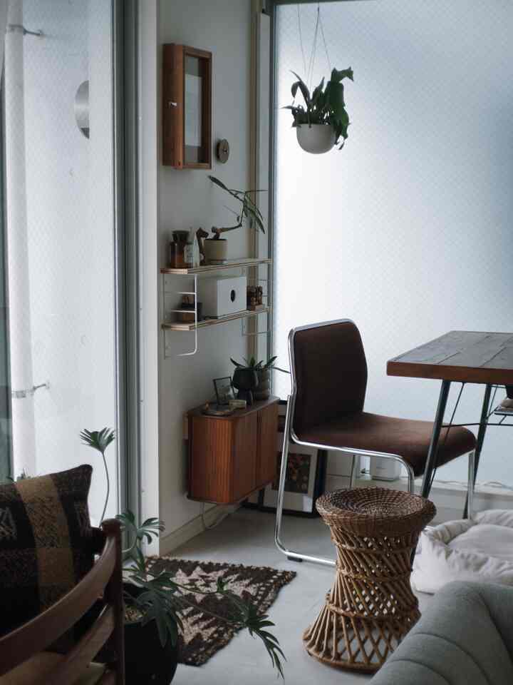 ナチュラルな色調のリビング、木製家具とダイニングチェア、植物が配置された雰囲気のあるインテリア