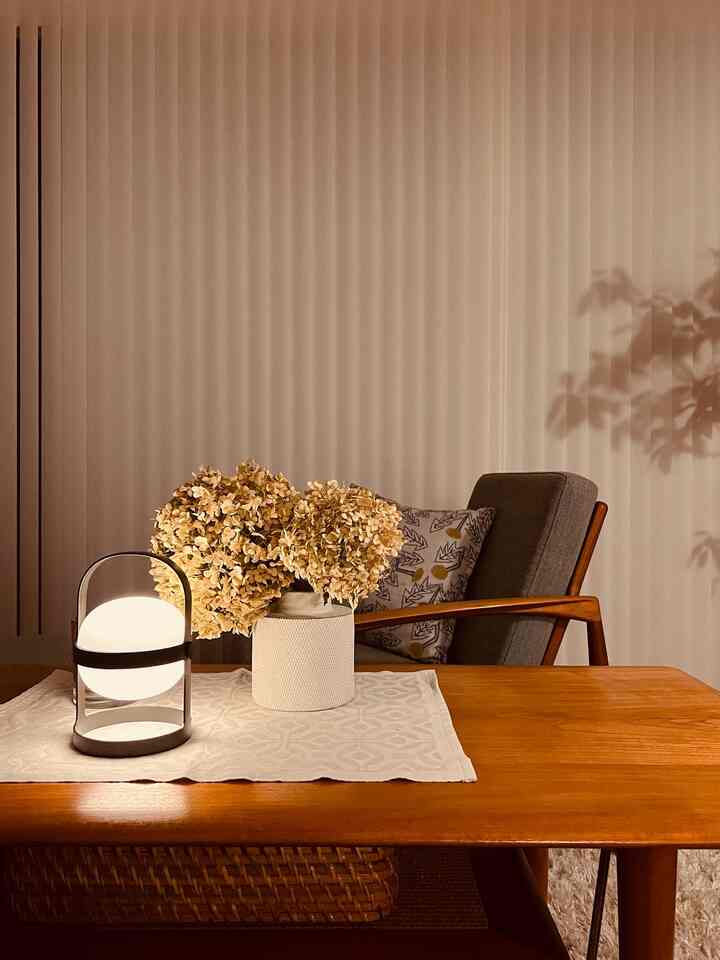 温かみのあるウッドトーンのナチュラルスタイルのリビングサイドテーブル、テーブルランプと花瓶が配置された雰囲気ある空間