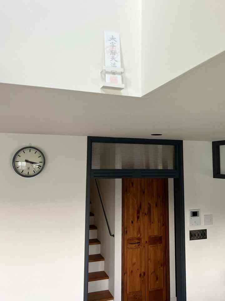 白い壁と自然な木目調のドアと階段が調和したシンプルな玄関と廊下の空間