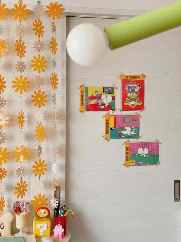 A cozy room with yellow and brown tones featuring a desk, floral garland, and cute illustrated posters on the wall