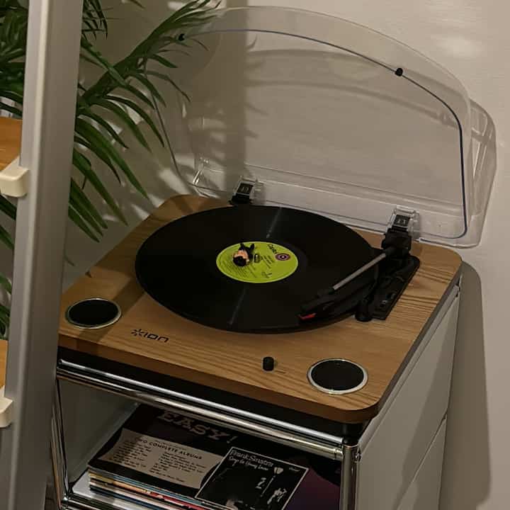 Simple music listening space featuring a natural wood-tone nightstand with a record player on top