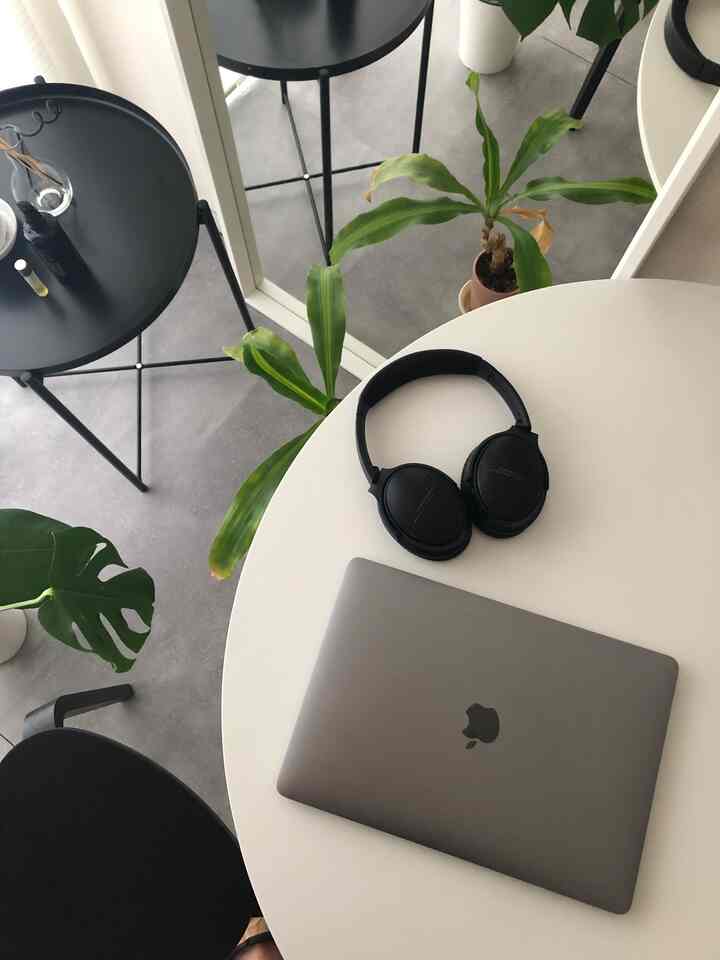 Monotone modern small home office featuring a white round table, black furniture, and green plants
