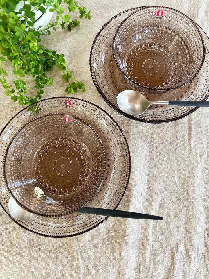 Natural-toned dining surface featuring transparent Scandinavian-style glass bowls and plates with spoons