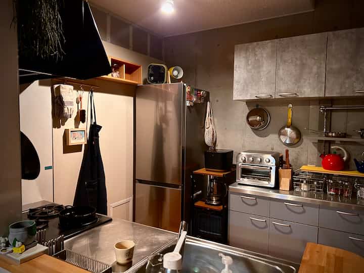 温かみのあるナチュラルな色調とステンレス調理台が配置されたコンパクトなワンルームキッチンの雰囲気のあるインテリア