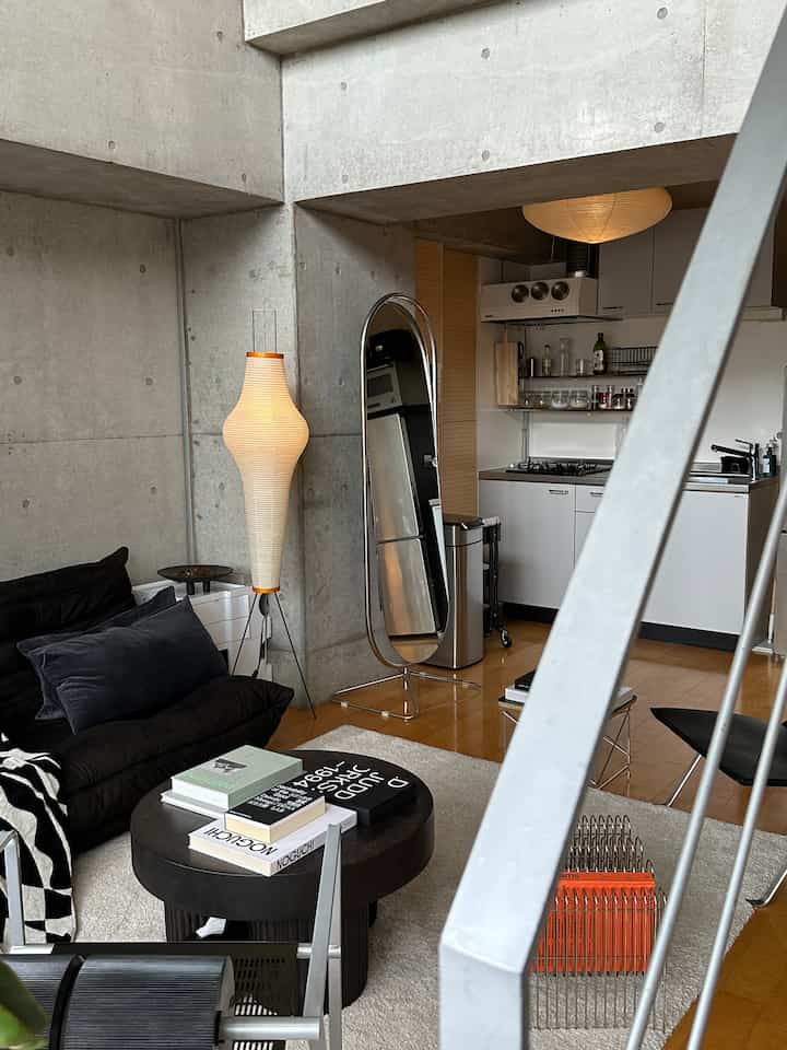 白と黒のトーンのモダンなリビング、コンクリートの壁とフロアランプが印象的な空間