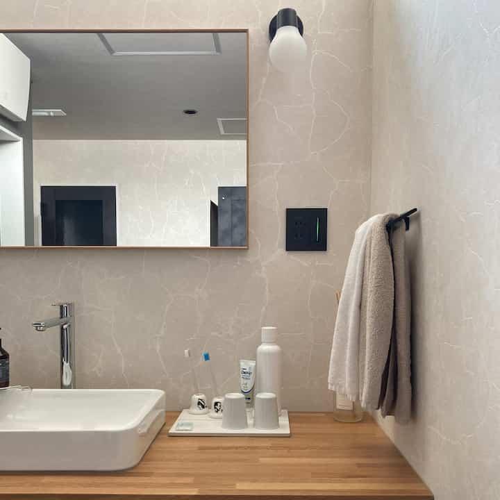 白と木目調が調和したバスルームの洗面スペース、タオルとオープン収納が配置された清潔感のあるインテリア