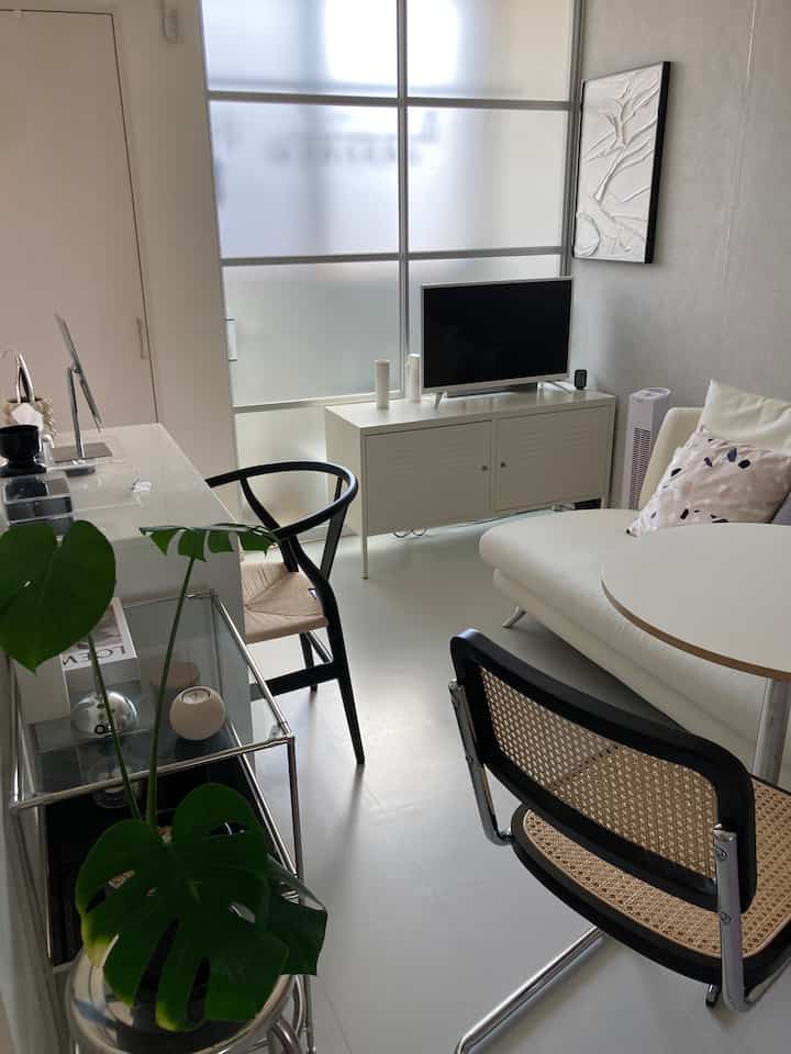 A white-toned living room with a modern and minimal atmosphere featuring a white sofa and metal cabinet