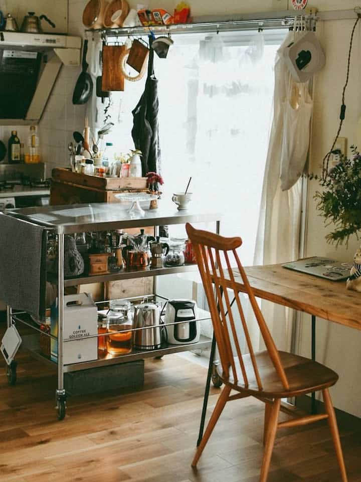 ナチュラルカラーと木目調のキッチン、ステンレスのキッチンワゴンと木製のダイニングチェアが配置された雰囲気のあるインテリア