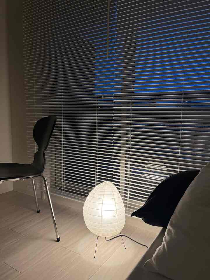 白を基調とした8畳のL字型の部屋、黒い椅子とクッション、卵形のフロアランプが温かみのある夜の雰囲気を演出している