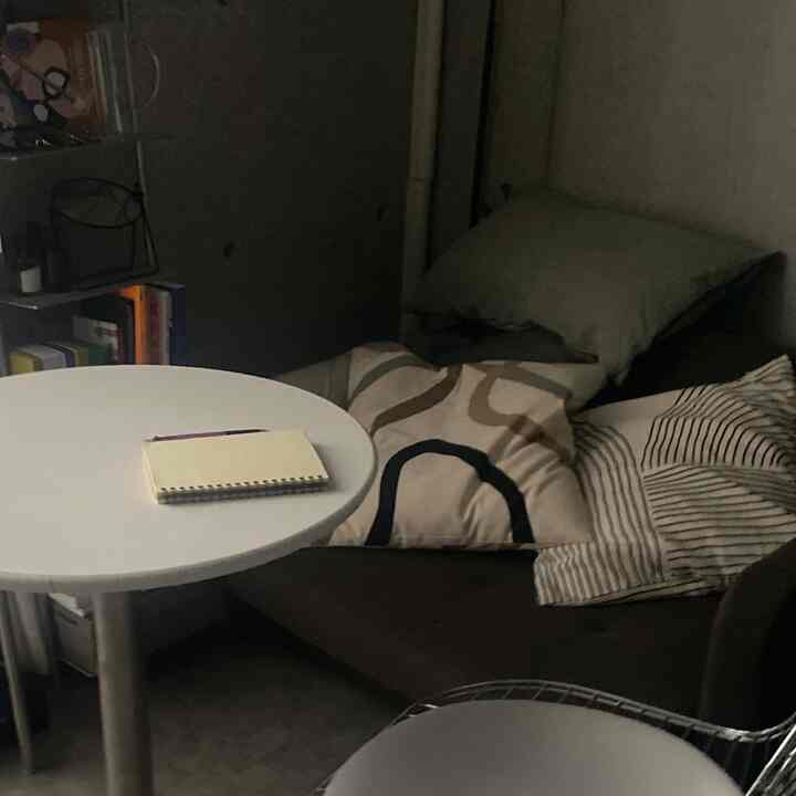 Dark-toned compact living room featuring a brown sofa bed and a white round table creating a cozy atmosphere