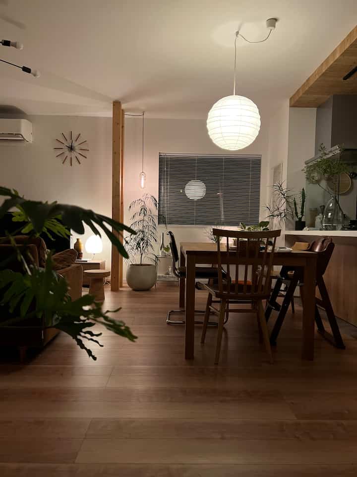 温かみのあるブラウンの木目調ダイニング、自然な植物と丸い和紙のペンダントライトが落ち着いた雰囲気を演出するインテリア