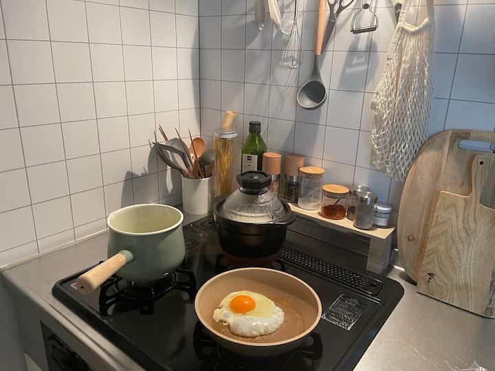 白いタイルの壁とナチュラルな木製調理器具が配された、コンパクトなキッチンの雰囲気あるインテリア