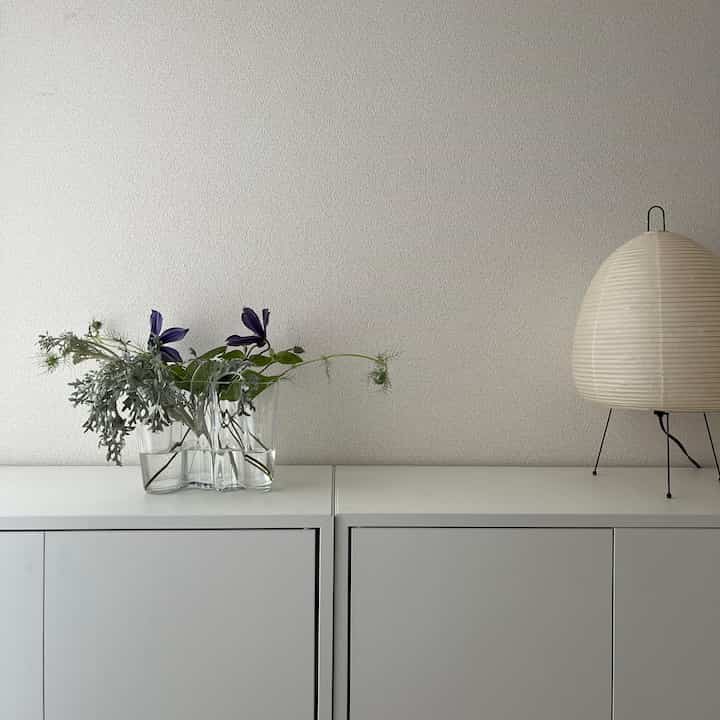 白を基調としたワンルーム空間にアルヴァ・アアルトの花瓶と三脚のフロアランプが置かれた、シンプルでナチュラルな雰囲気のインテリア