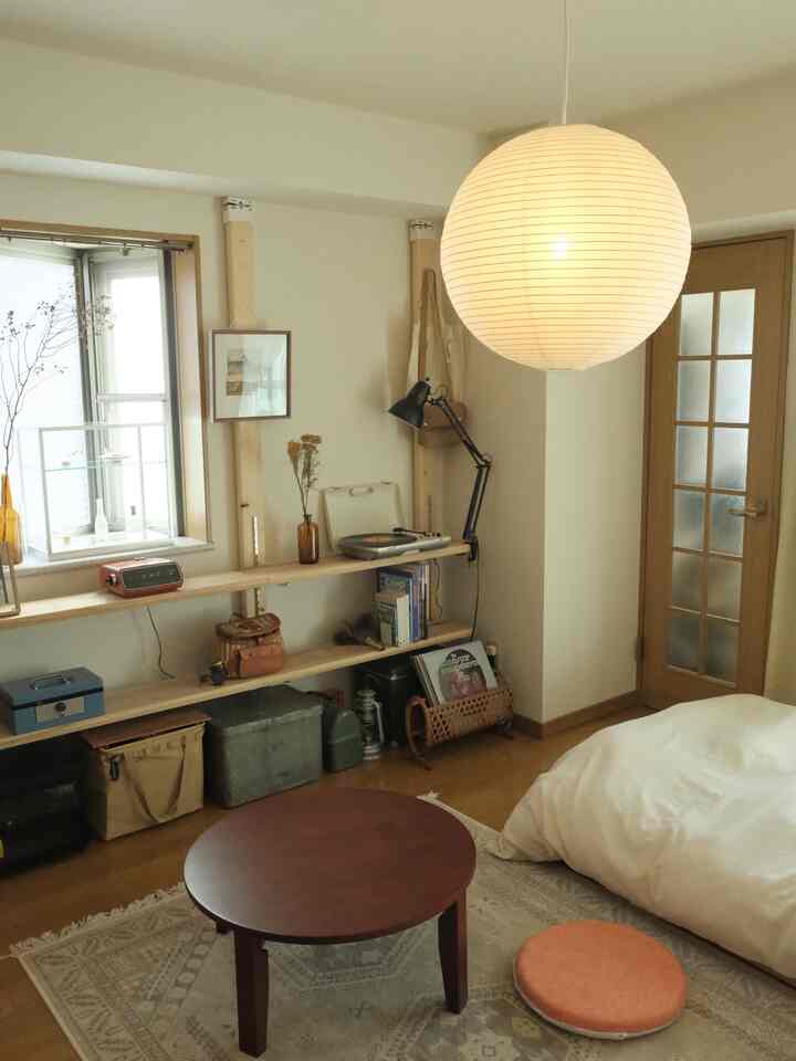 Natural-toned bedroom in white and light brown featuring round coffee table and Japanese paper pendant light