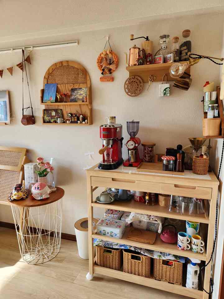 ベージュの壁と木目調のキッチンワゴンがあるナチュラルなおうちカフェ空間、中央にエスプレッソマシンとグラインダーが配置されている