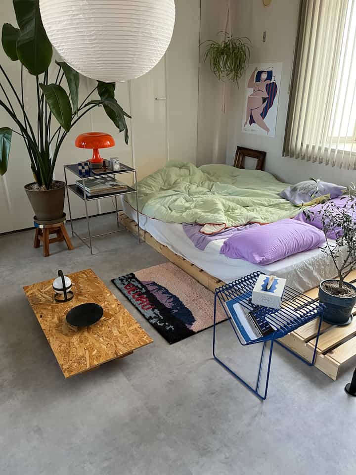 Natural wood tone and white-toned bedroom featuring a low bed and side table in a modern minimal setting