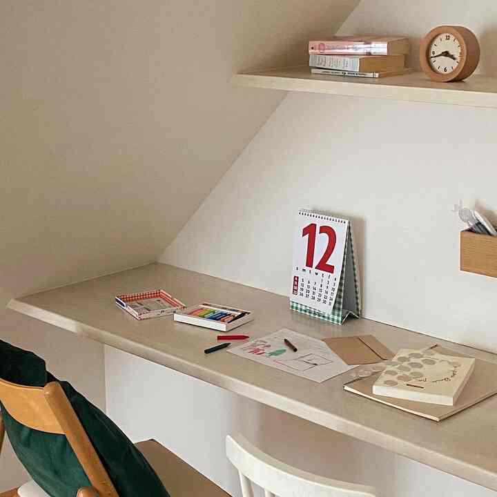 ナチュラルなベージュ色の壁と机、子供用の椅子とクレヨンが配置された印象的な子供の学習スペース