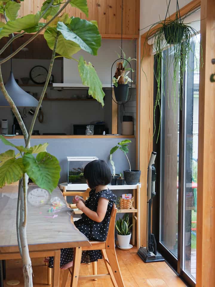ナチュラルな木目調と緑の植物が配置された、子供と暮らす印象的なダイニングルーム