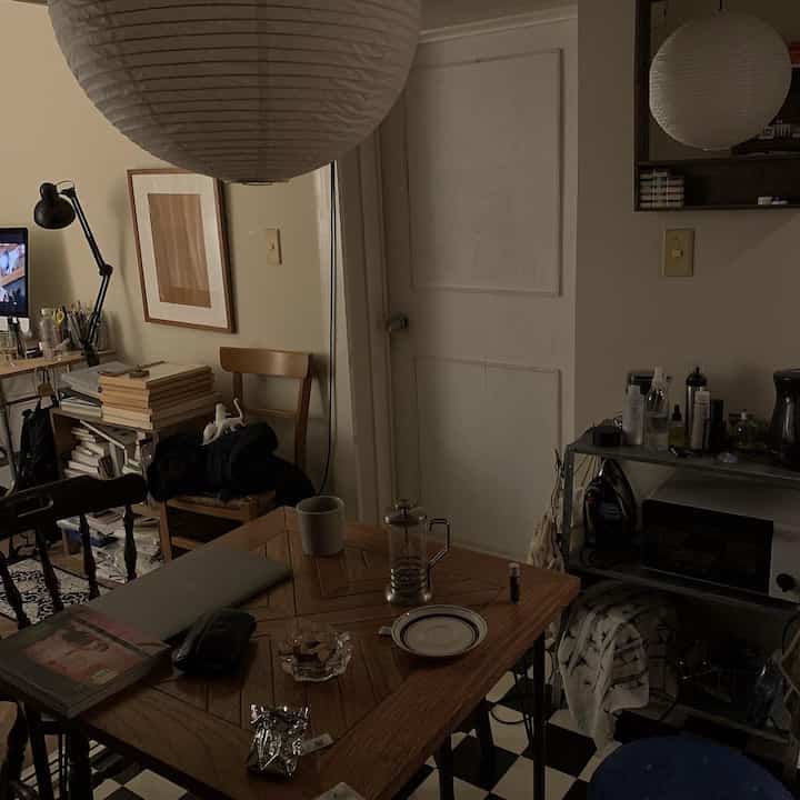 White and wood-tone compact apartment dining space featuring home cafe elements and remote work setup with cozy atmosphere