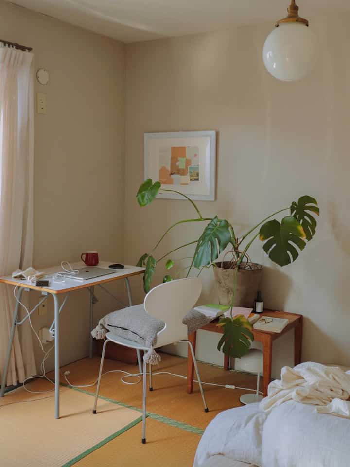 Light beige compact tatami room featuring a desk, chair, large plant, and natural home office setup