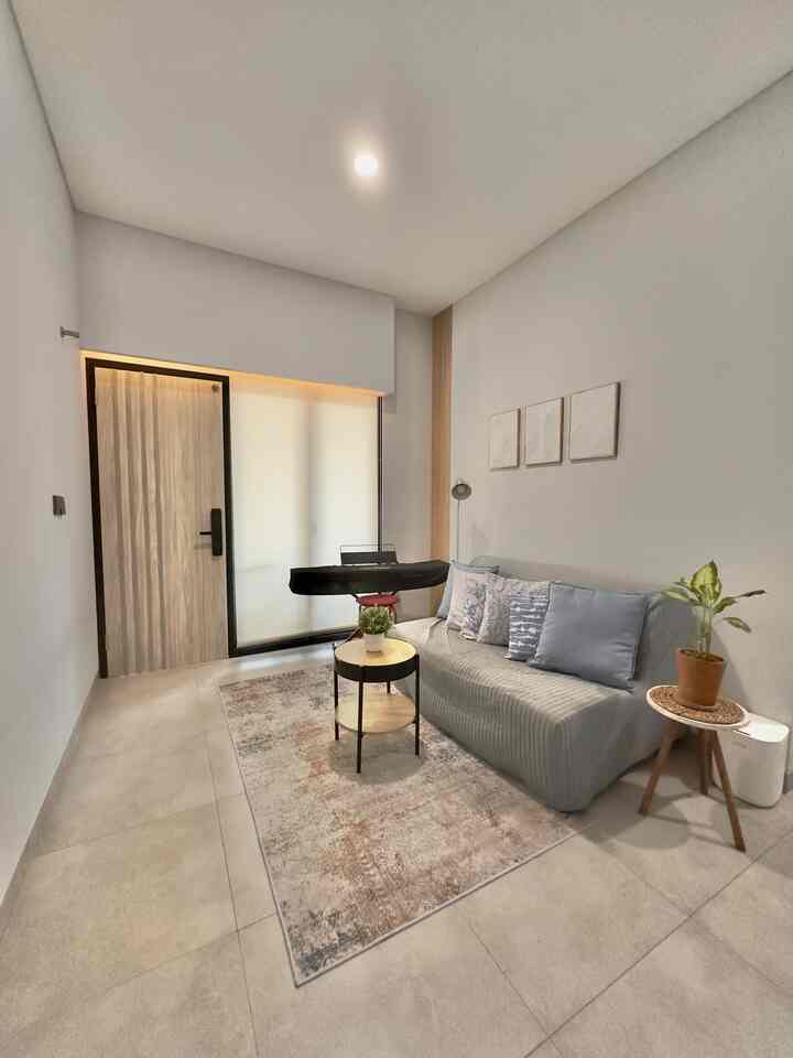 Modern industrial style living room with gray sofa, wooden tables, and white walls in a compact space