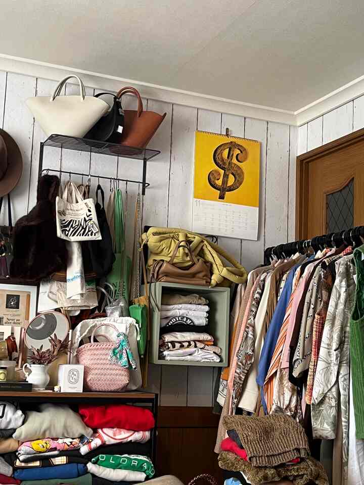 White and brown wood-tone small closet room featuring racks and shelves loaded with bags and folded clothes