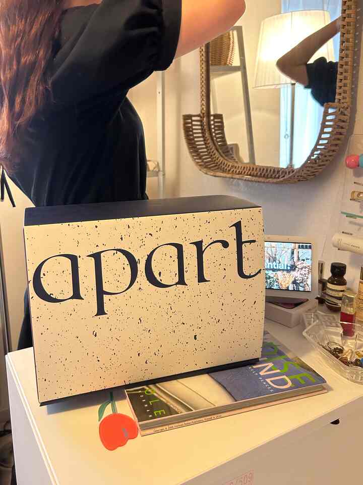 A cozy bedroom vanity area featuring a white desk and a brown rattan mirror with soft lighting
