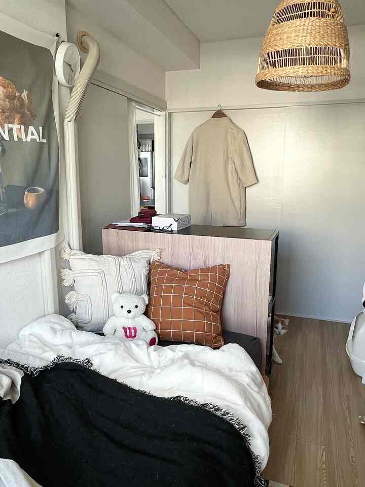 White and brown tone bedroom featuring bed with pillows and storage cabinet in a cozy space