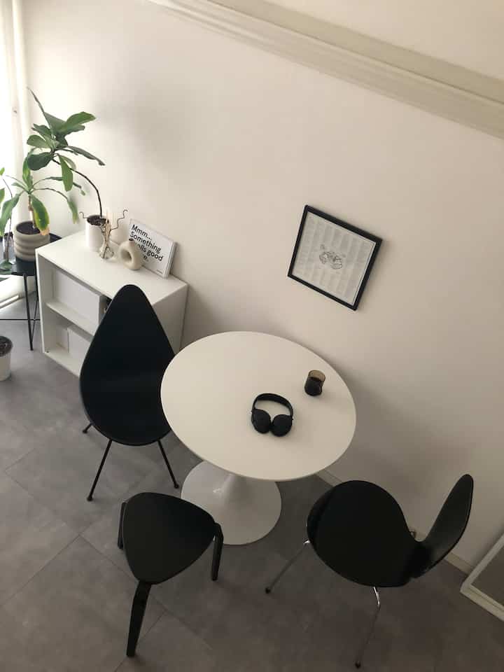 A white and black toned dining room featuring a round dining table and stools, creating a minimalist and modern atmosphere